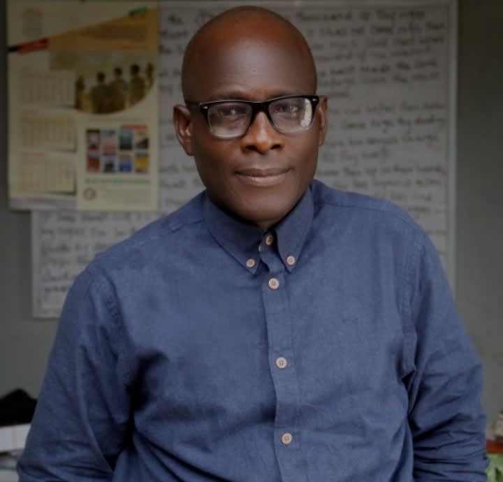 Charles O. Ajayi wearing glasses and a blue shirt
