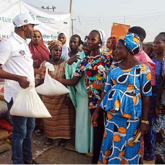 A DRF volunteer handing out white bags of food to a group of women