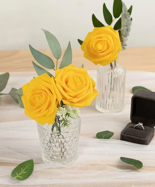 Yellow artificial roses in bud vases on an event table