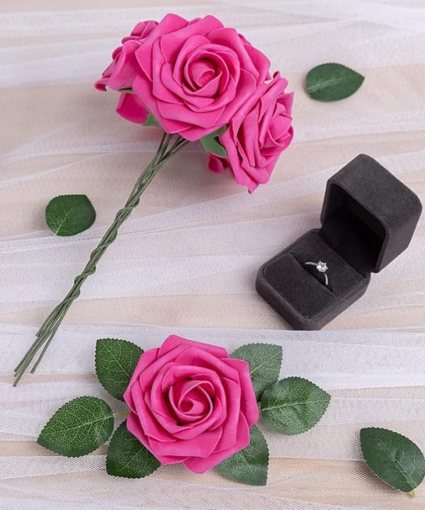 Pink artificial roses beside a ring box, styled as a gift