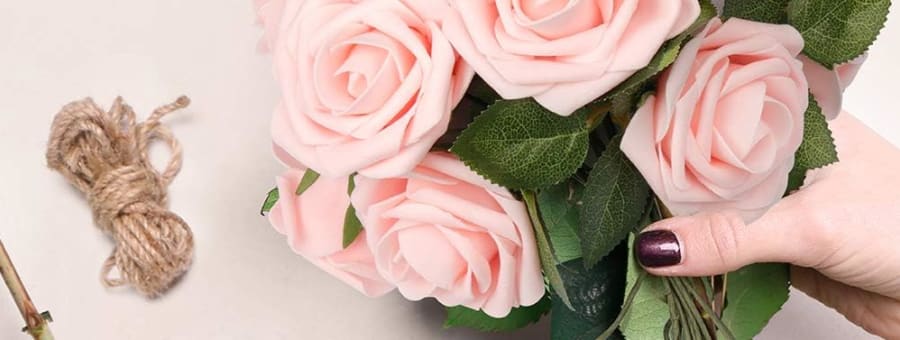 Hands arranging a bouquet of pink artificial real-touch roses