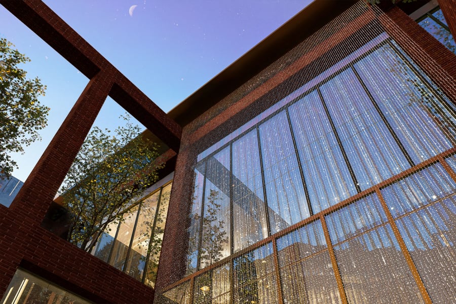 Modern brick and glass building exterior at dusk featuring decorative beaded curtain facade and geometric architectural elements