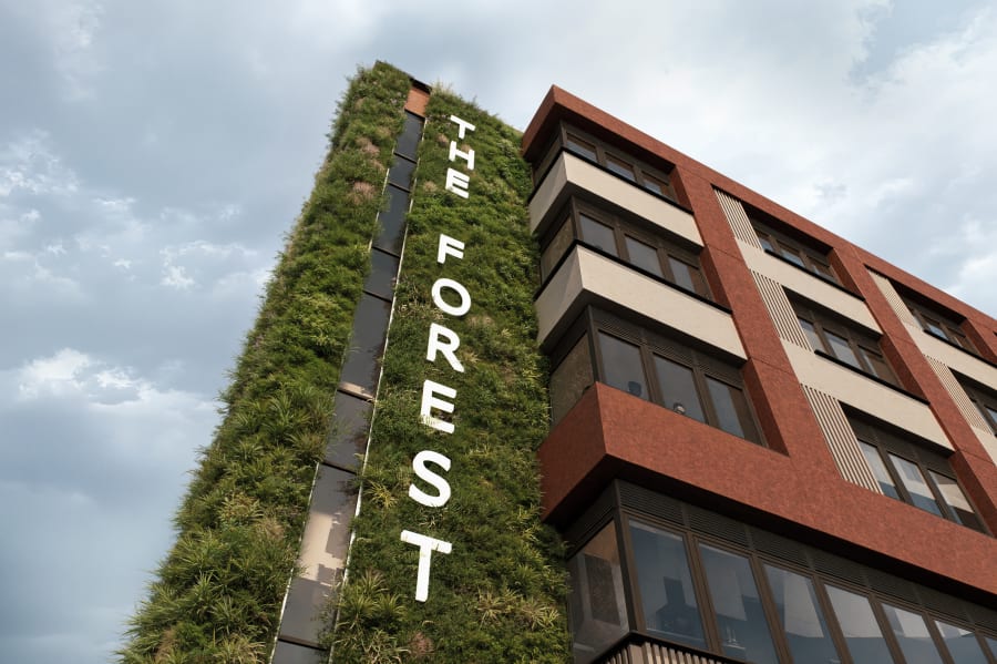 The Forest building exterior featuring vertical green living wall with white lettering and red brick facade with balconies