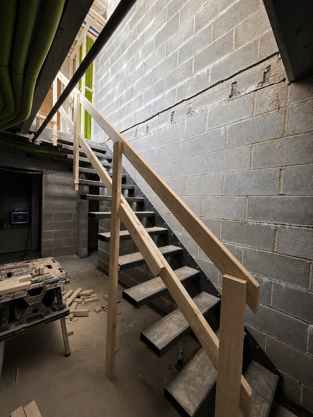 Unfinished staircase with a temporary timber handrail inside the building