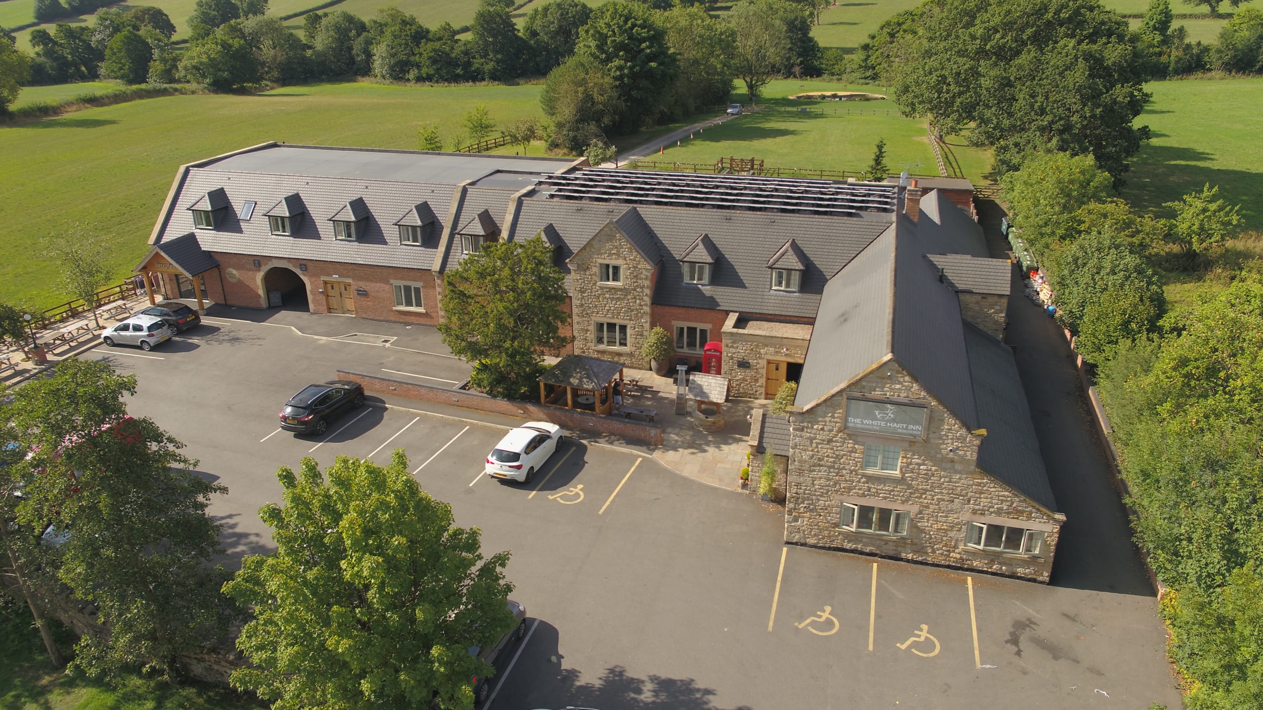 Aerial view of a stone leisure venue and car park surrounded by fields