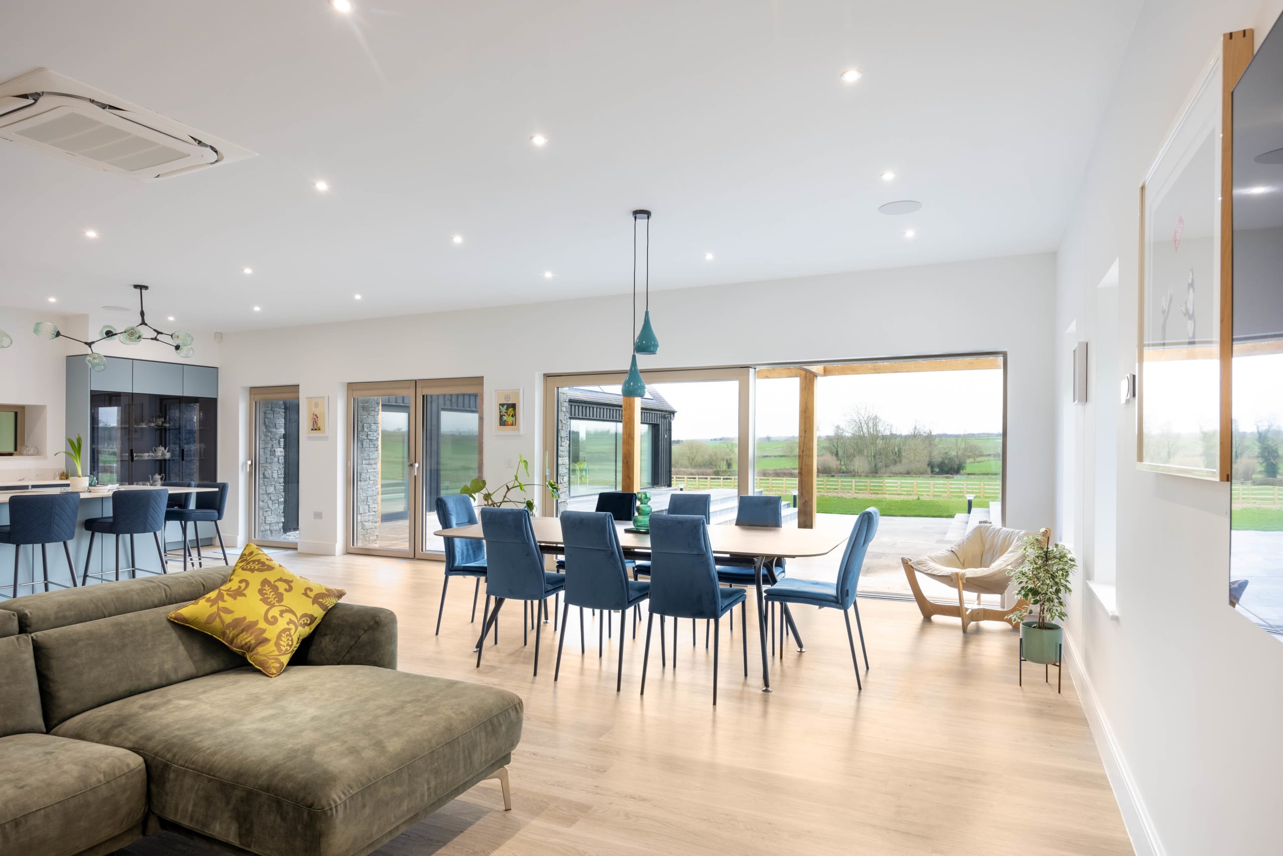 Open-plan kitchen, dining and living space with large glazed doors opening to countryside views
