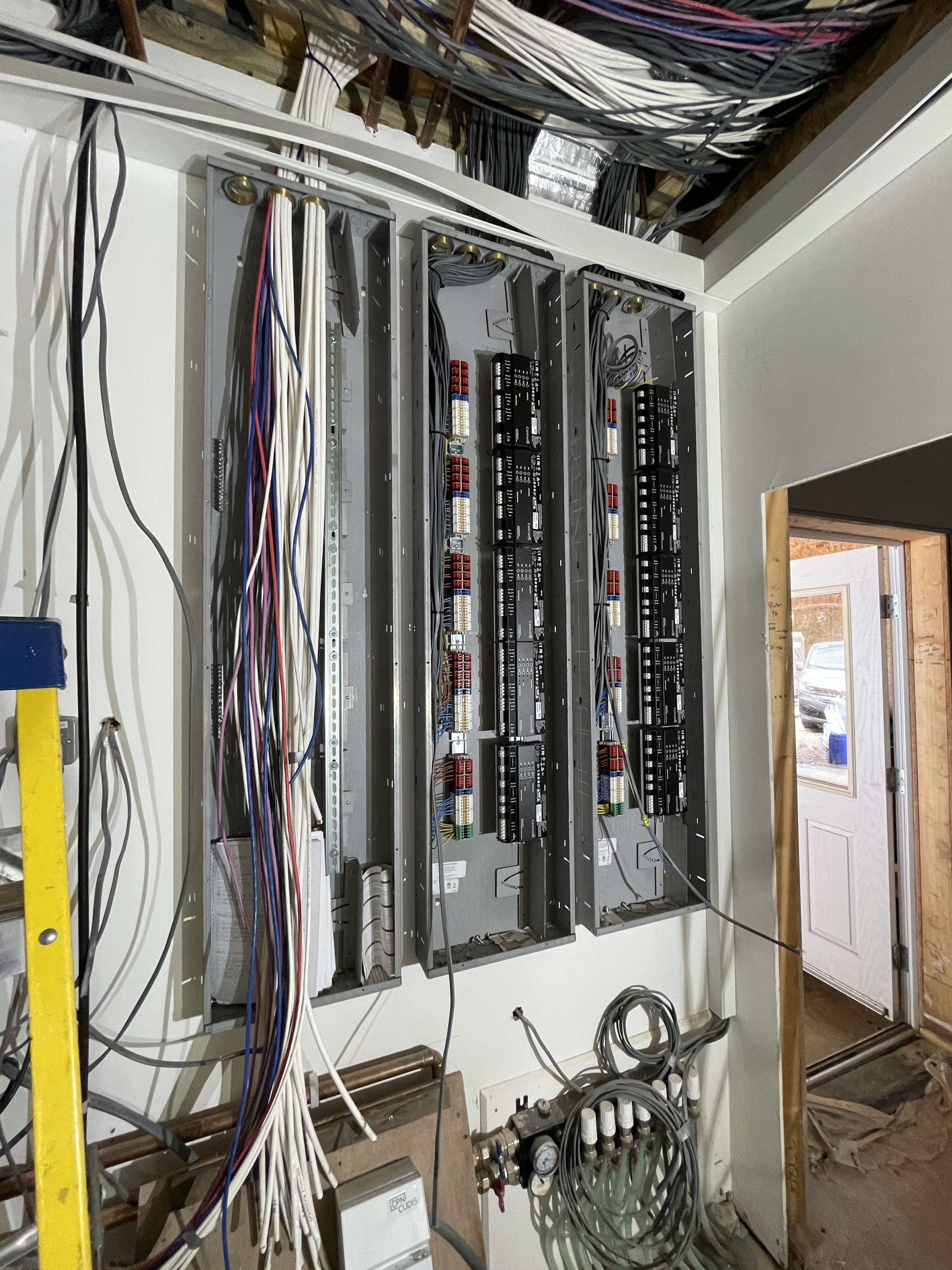 Large electrical panel installation with multiple breaker boxes and exposed wiring during commercial building construction