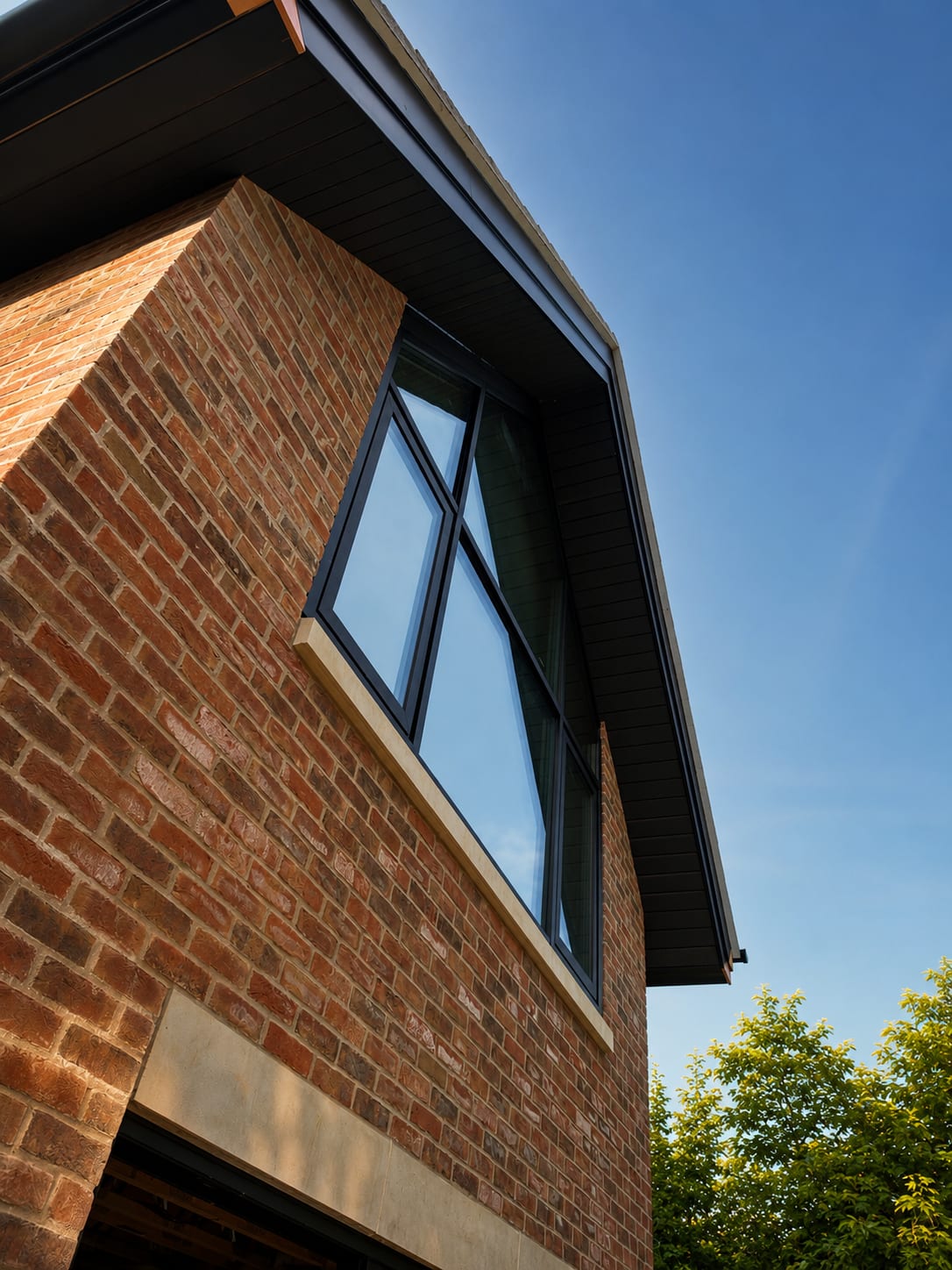Close-up of the brick gable and dark-framed upper window during construction