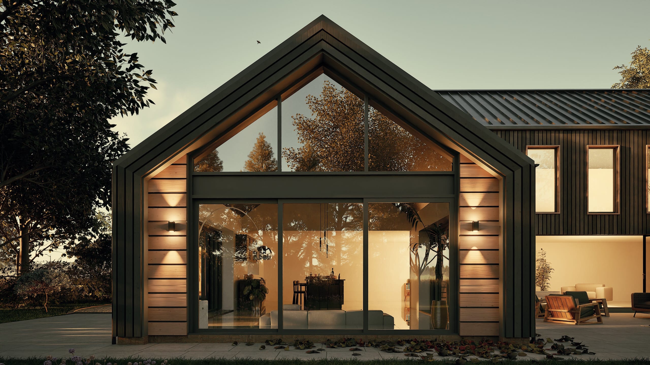 Modern barn-style home at dusk featuring floor-to-ceiling glass gable windows, warm interior lighting, and dark metal siding