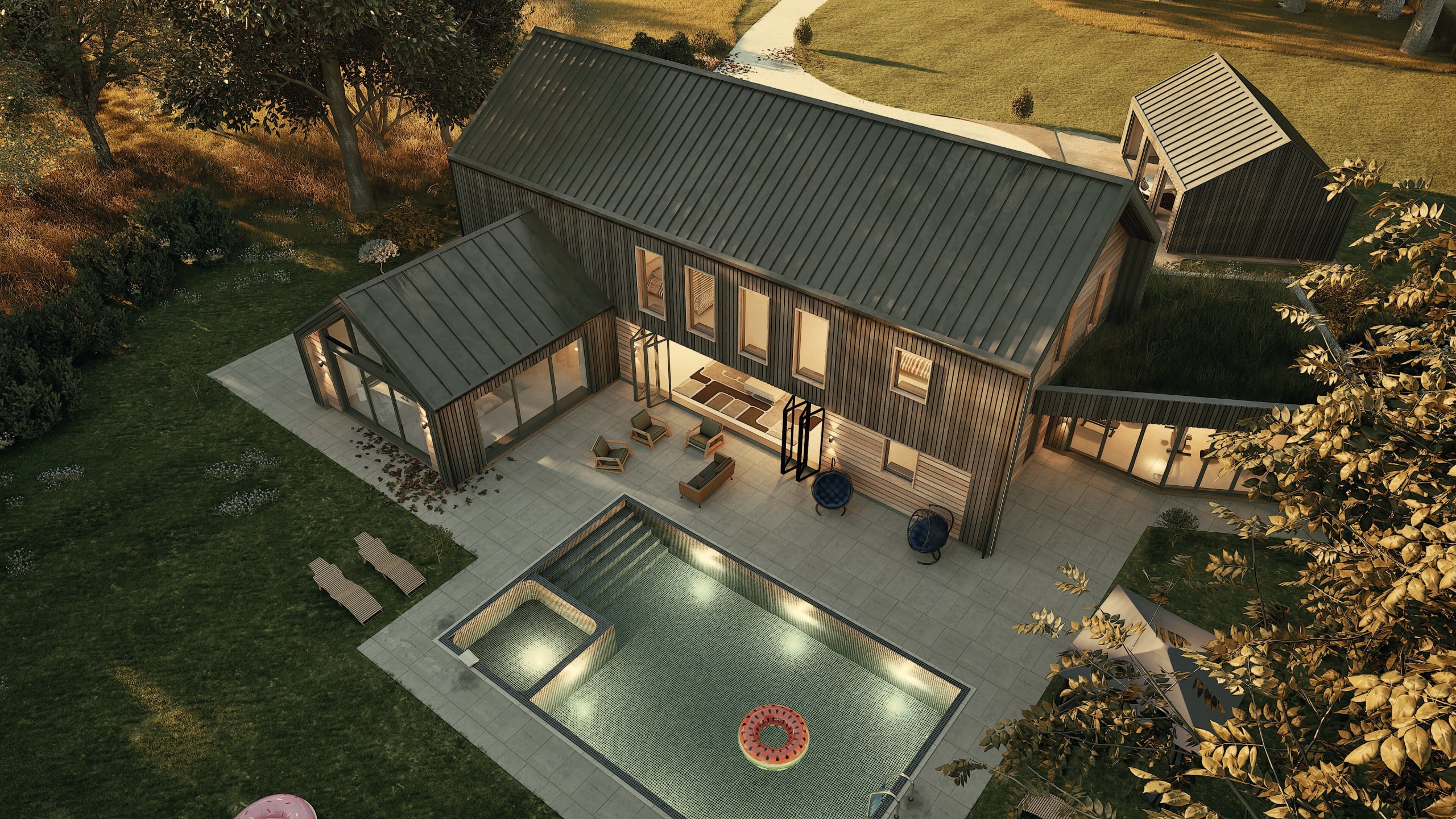 Aerial view of modern barnhouse with metal roof, covered patio, swimming pool with hot tub, and landscaped grounds at dusk