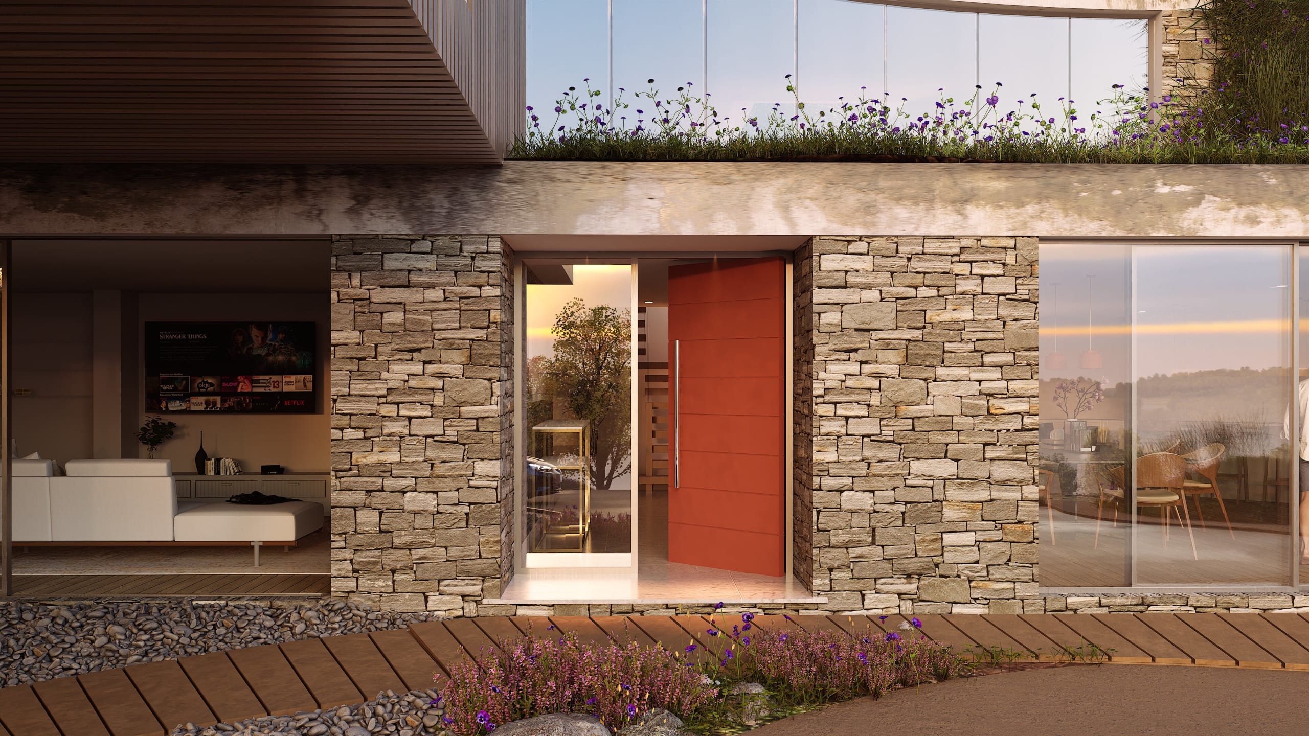 Modern home entrance featuring stacked stone walls, bold red pivot door, wooden deck walkway, and rooftop garden with flowers