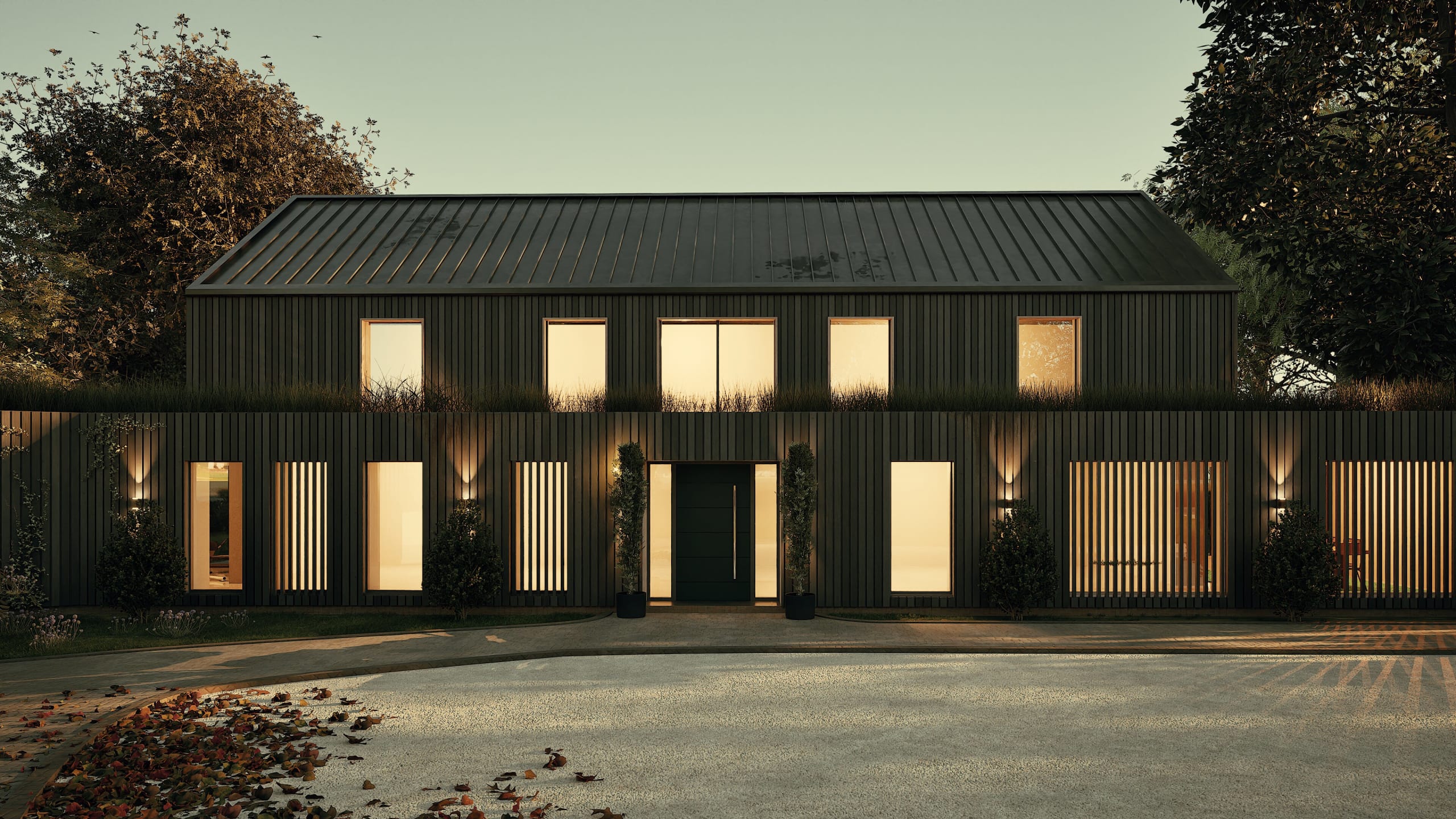 Modern two-story black timber-clad home with standing seam metal roof, illuminated windows, and vertical slat details at dusk