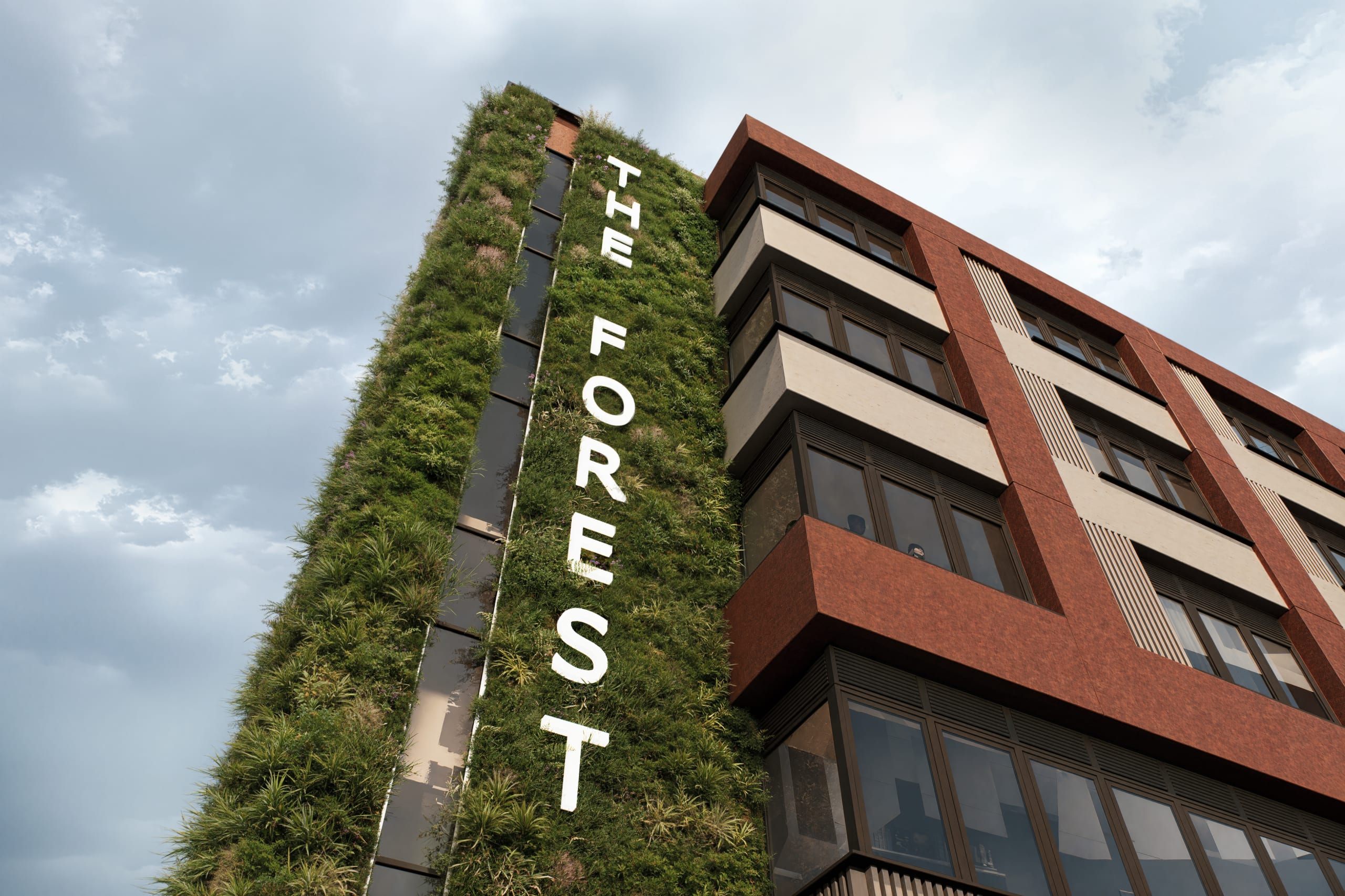 The Forest building exterior featuring vertical green living wall with white lettering and red brick facade with balconies