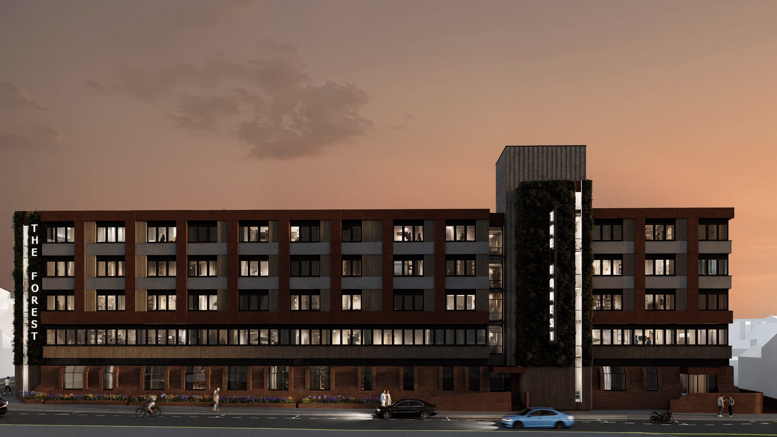 The Forest mixed-use building exterior at dusk featuring brick and dark metal facade with vertical green wall accent