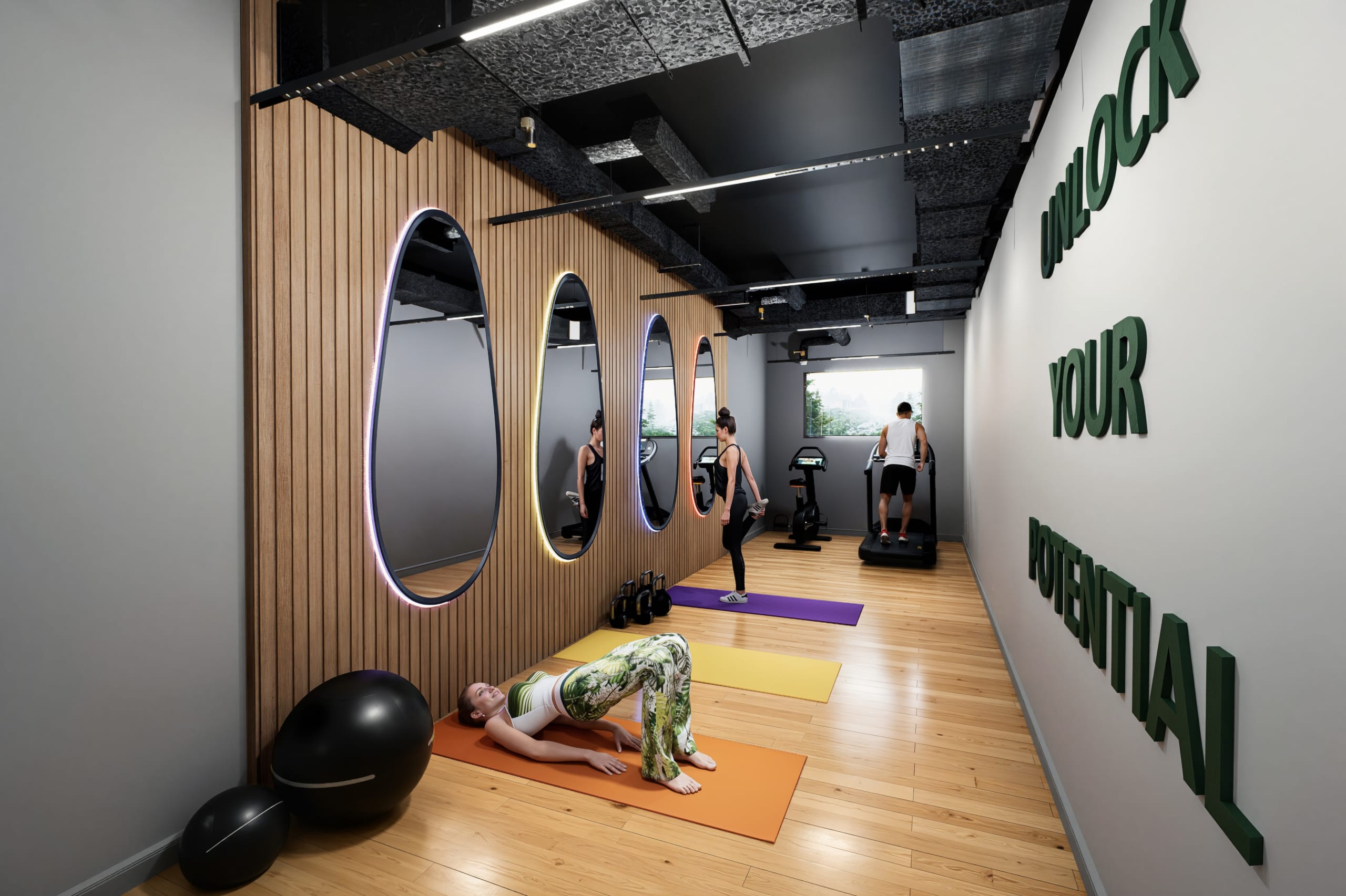 Modern fitness studio with wood-paneled walls, oval LED mirrors, yoga mats, and cardio equipment with motivational wall text