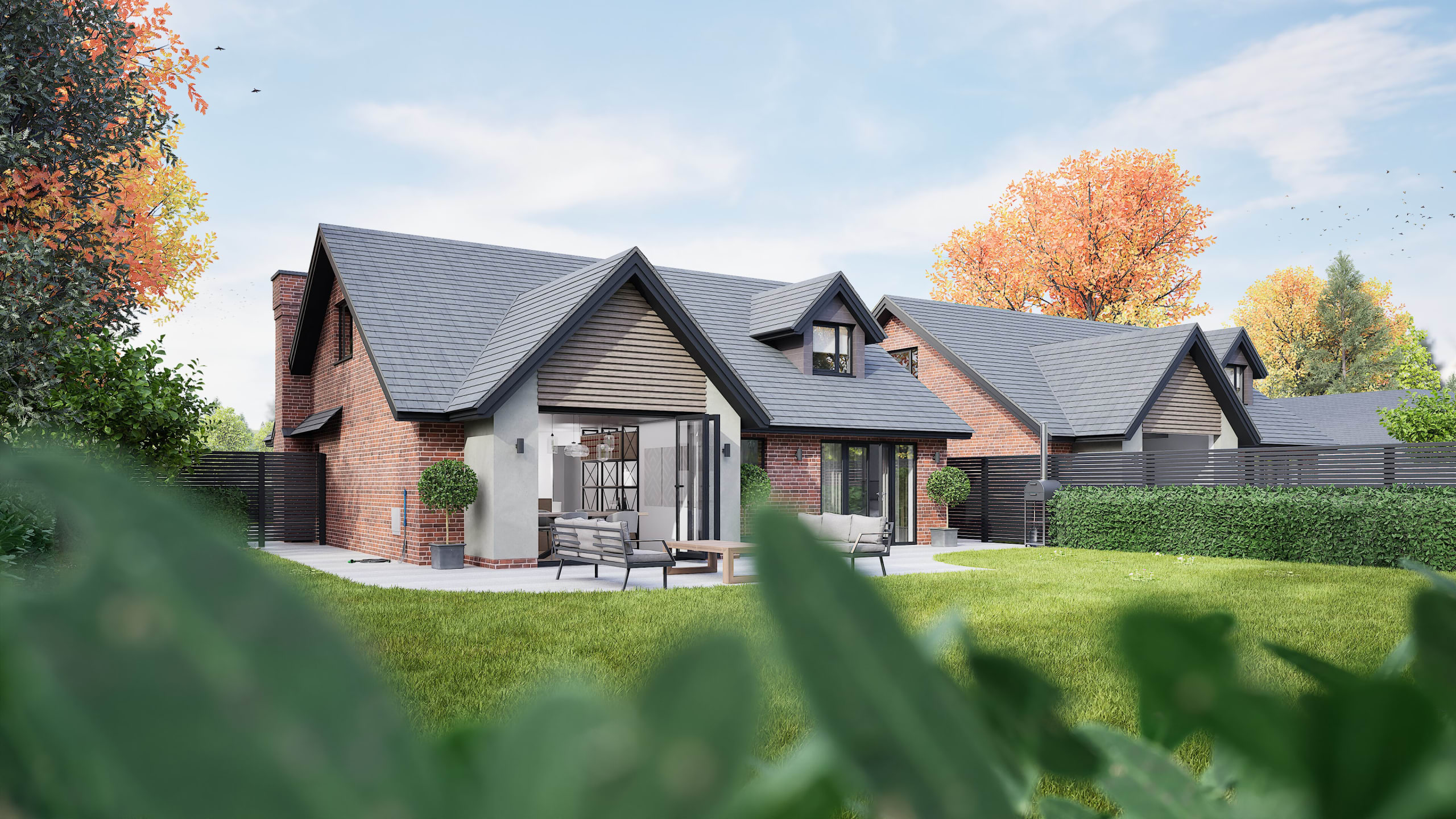 Modern brick home with grey slate roof, multiple gables, outdoor patio seating area, and landscaped garden in autumn