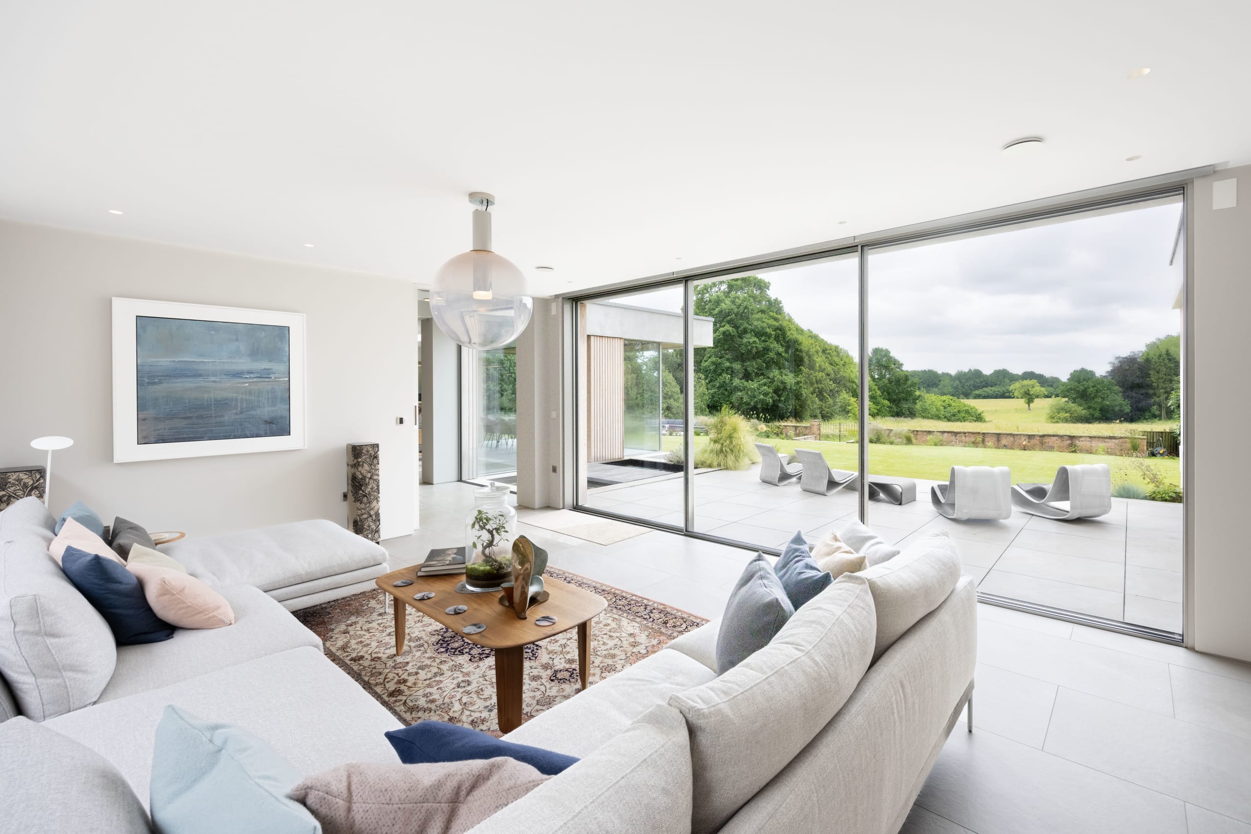 Living room with grey sectional sofa opens via full-width sliding glass doors to a patio and lawn