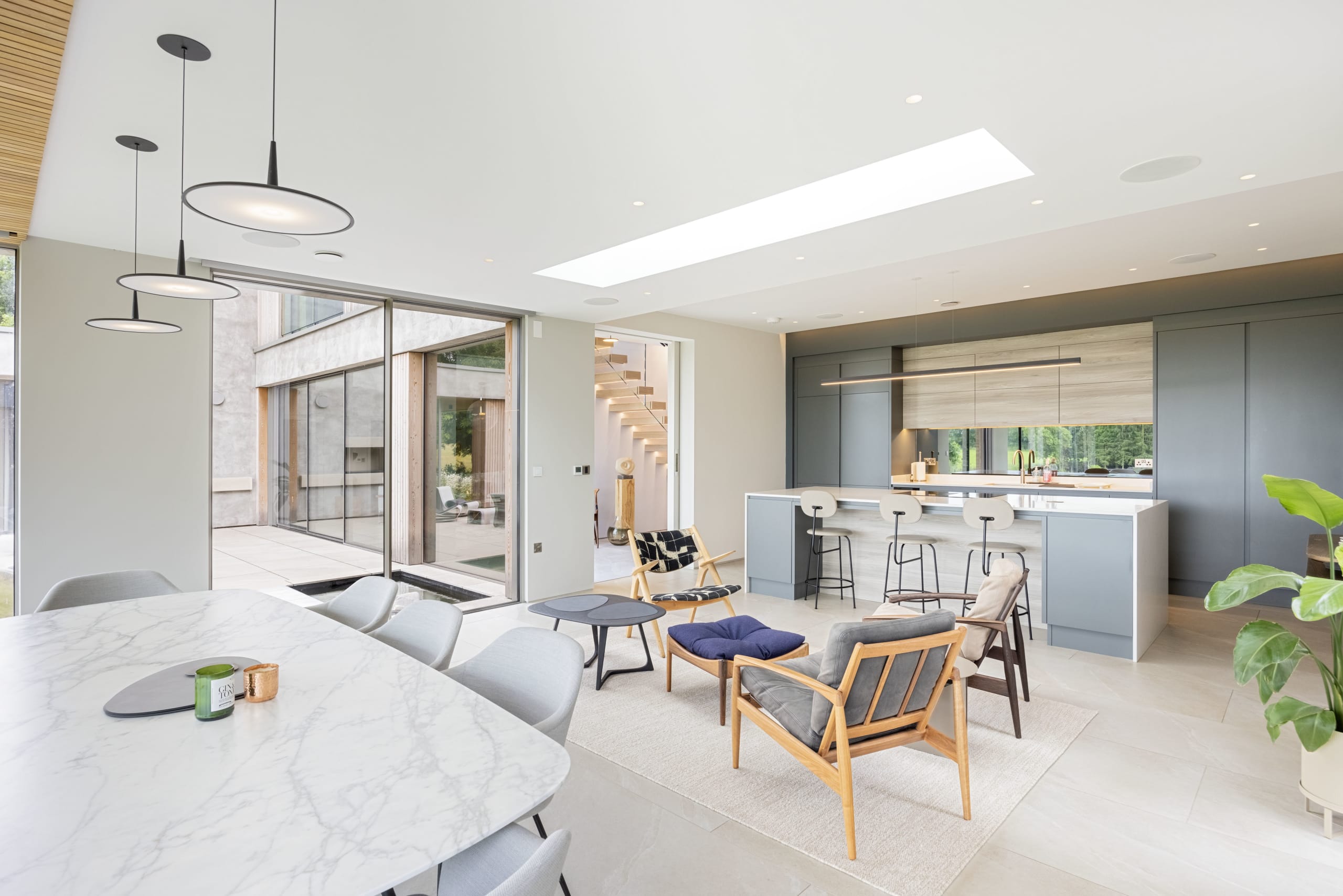 Open-plan living space with marble dining table, matte grey kitchen island, and skylight above