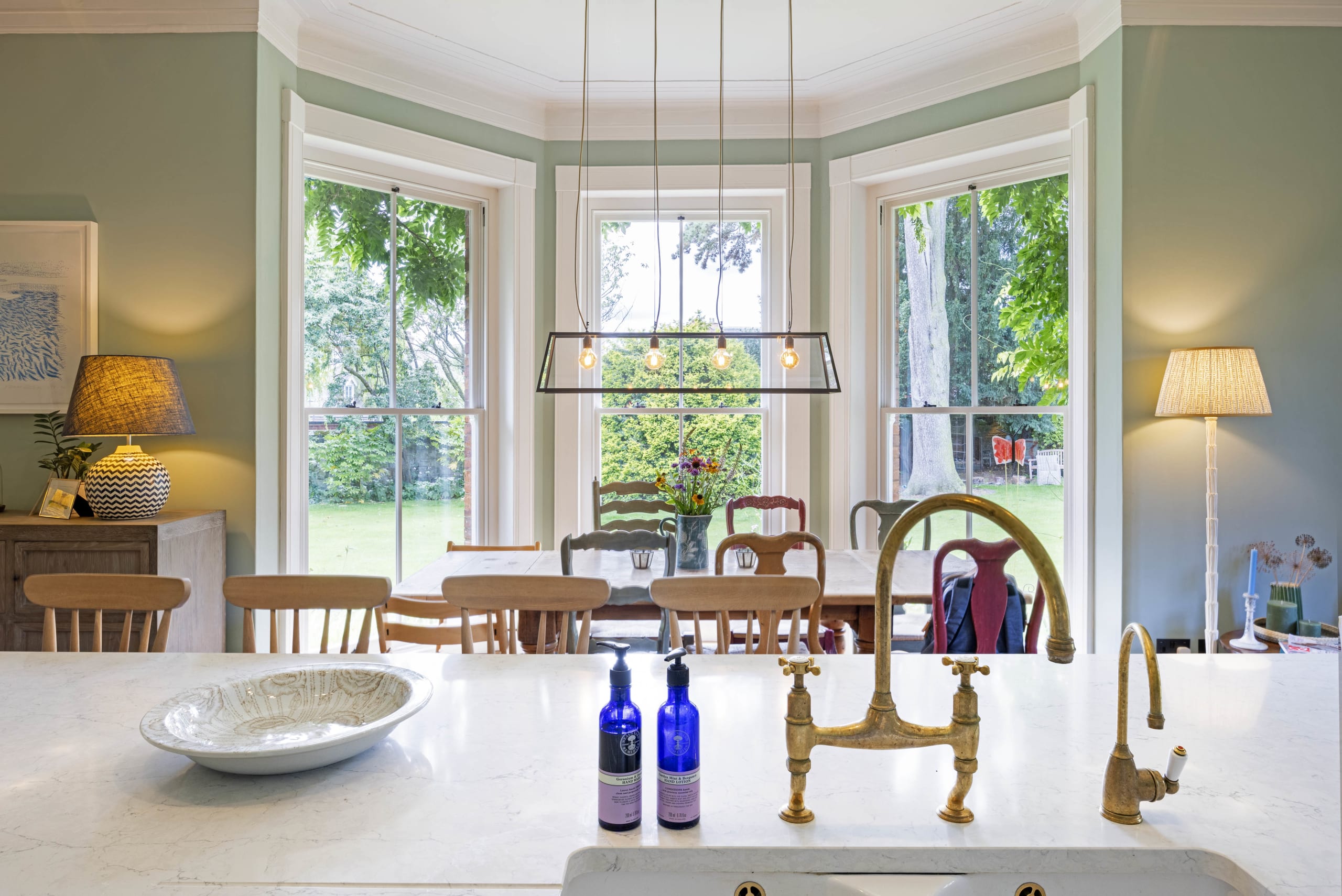 Period bay window dining area with brass kitchen taps and marble island in the foreground