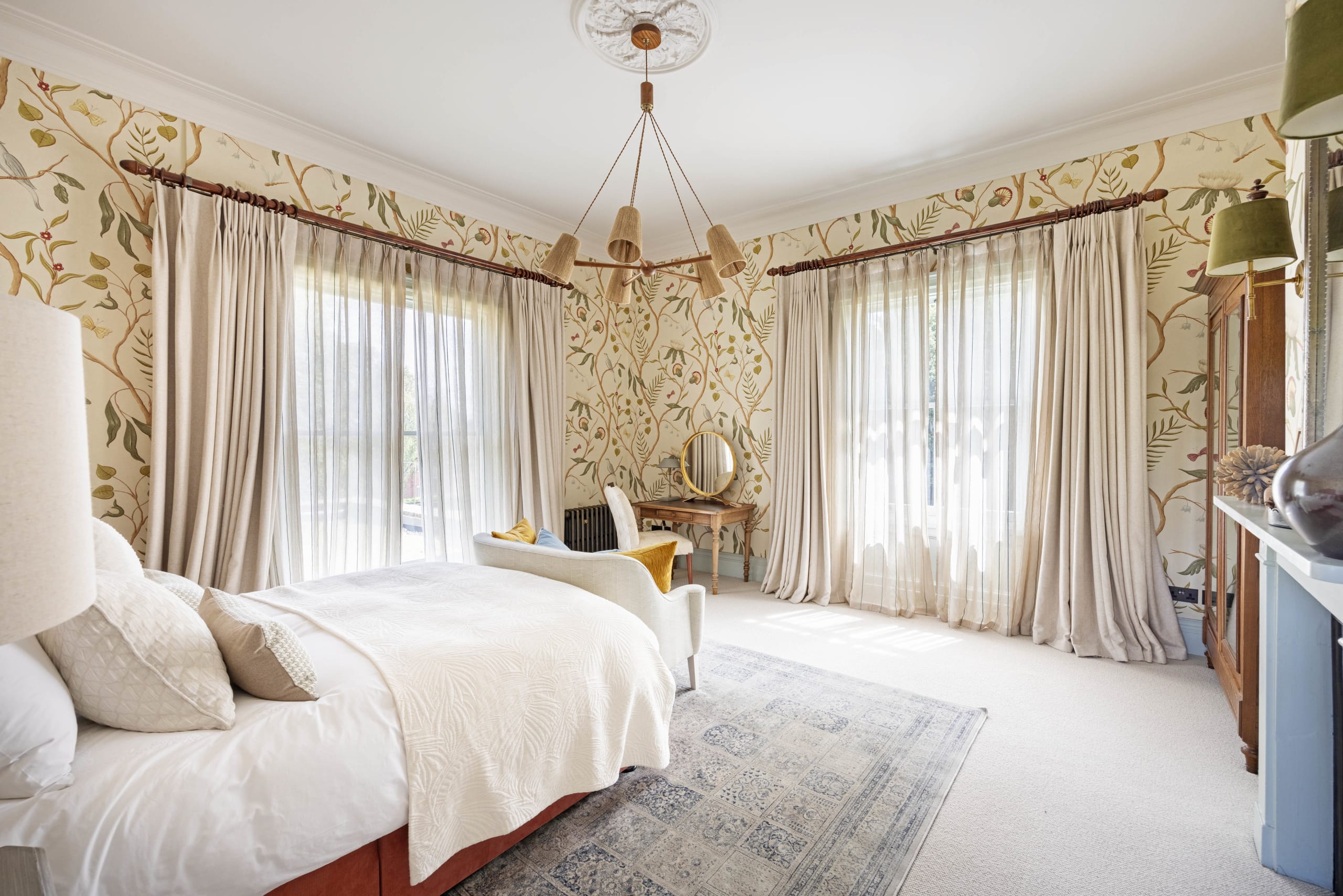 Traditional bedroom with botanical wallpaper, floor-length curtains, a multi-arm pendant light and a vintage rug