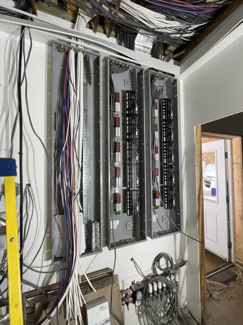Large electrical panel installation with multiple breaker boxes and exposed wiring during commercial building construction