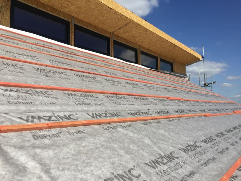VMZINC roofing membrane installation on sloped roof with DuPont Tyvek underlayment and wooden battens during construction