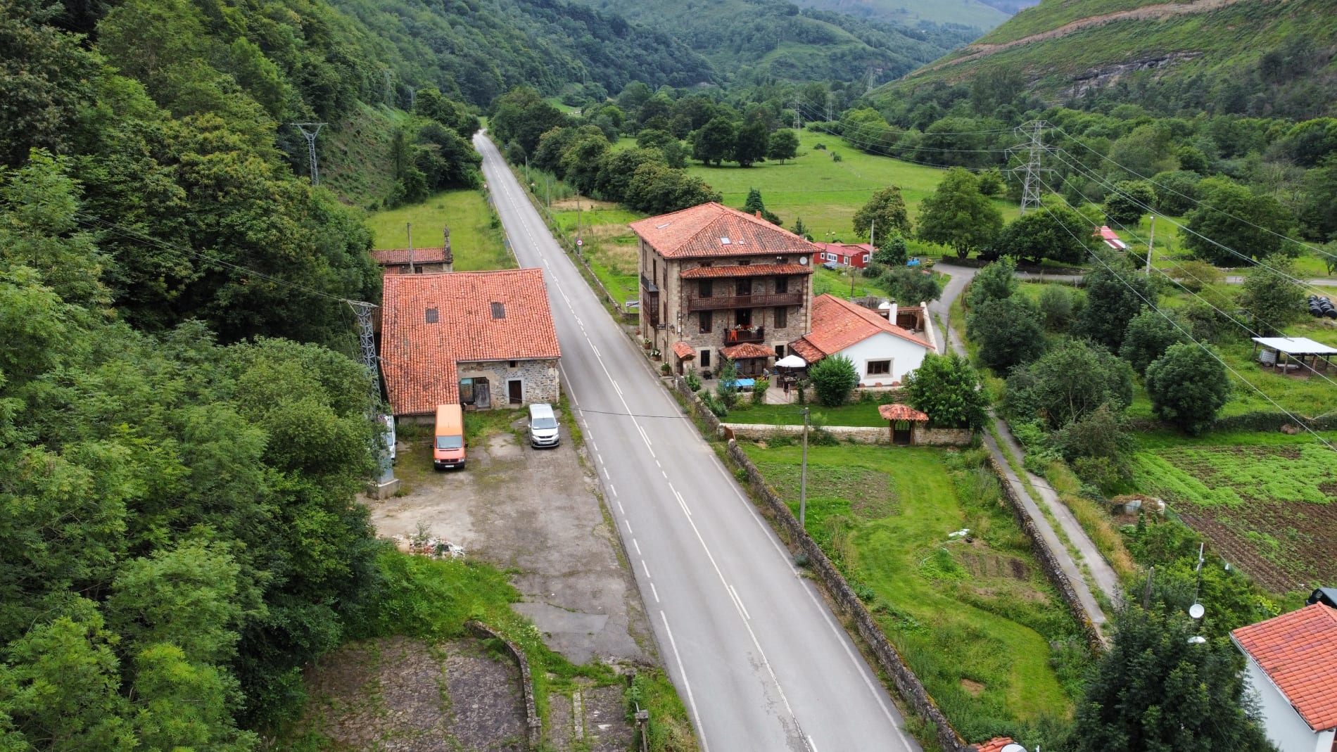 La casona de Agara desde el aire: torre de piedra, balcones y terraza en el valle de Cabuérniga