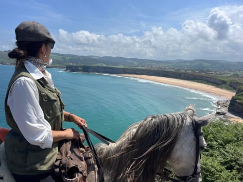 A rider above a turquoise cove on the clifftop