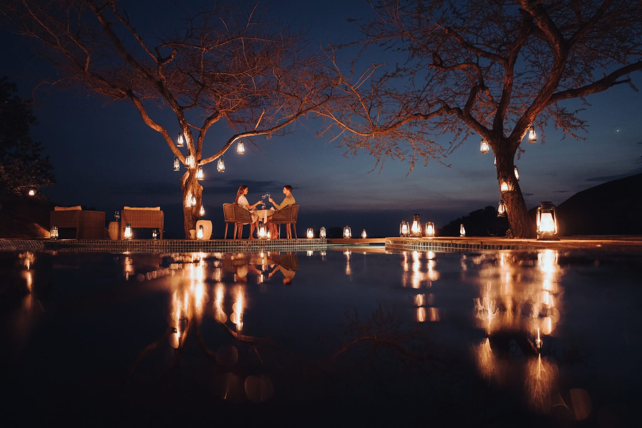 Romantic bush dinner table set by lantern light in the Serengeti at night, Tanzania honeymoon safari