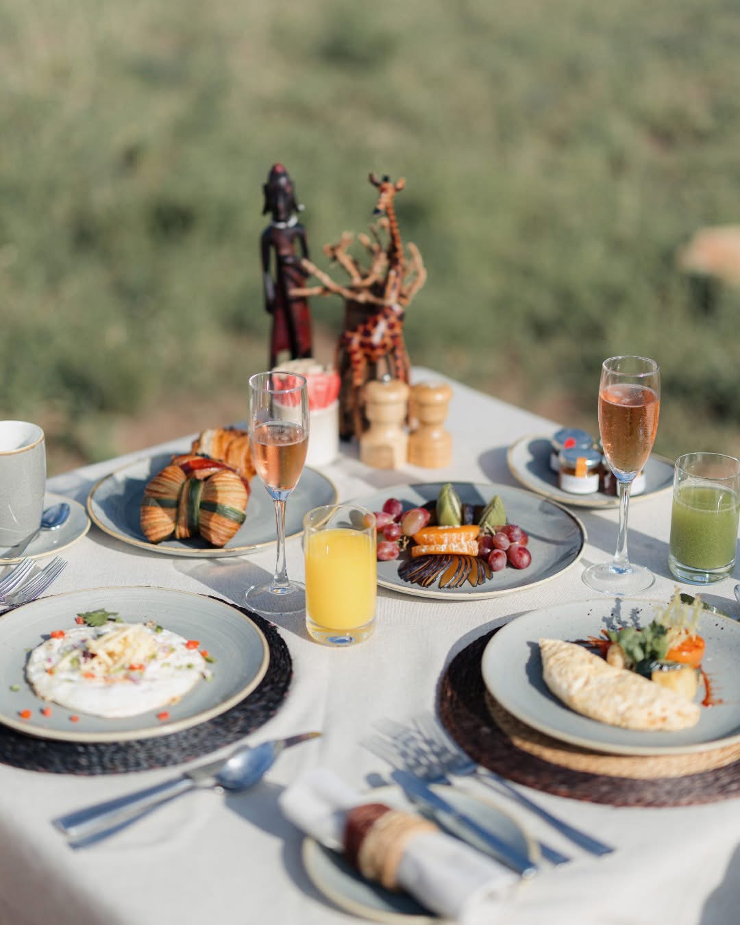 Luxury bush breakfast setup with champagne, fresh fruit, and eggs in the Serengeti
