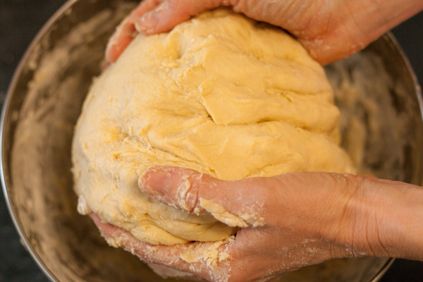 Hands kneading sourdough discard pretzel dough until smooth and elastic.
