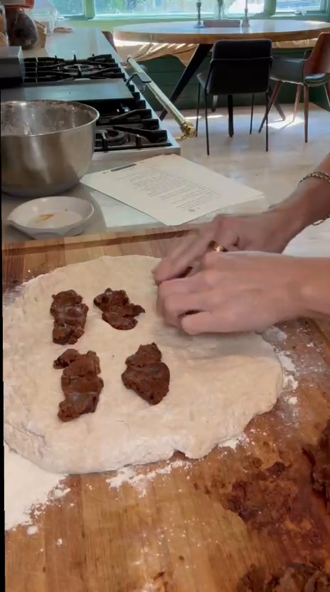 Chocolate chip cookie dough pieces being added to homemade bread dough before shaping the loaf.