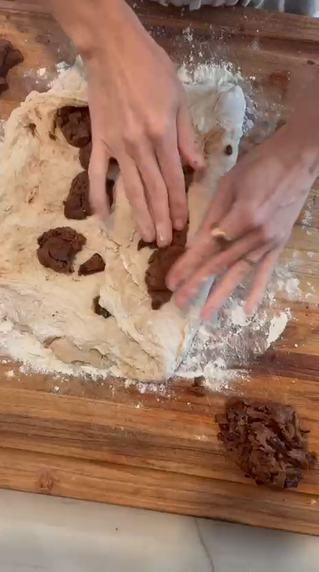 Bread dough being folded around chocolate chip cookie dough to distribute the filling throughout the loaf.