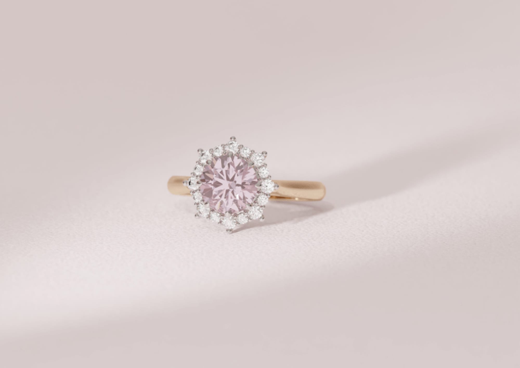 Pink diamond with a traditional diamond halo in a yellow gold band