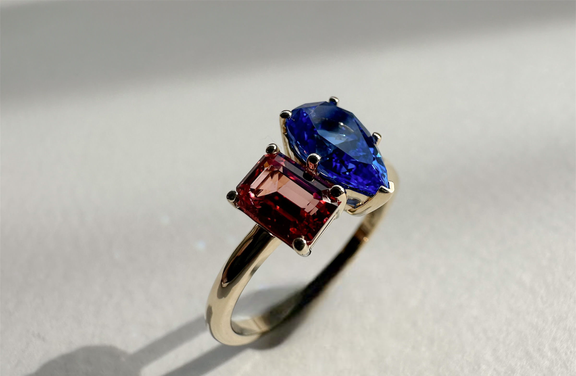 Toi et moi featuring emerald cut red moissanite and pear cut blue sapphire