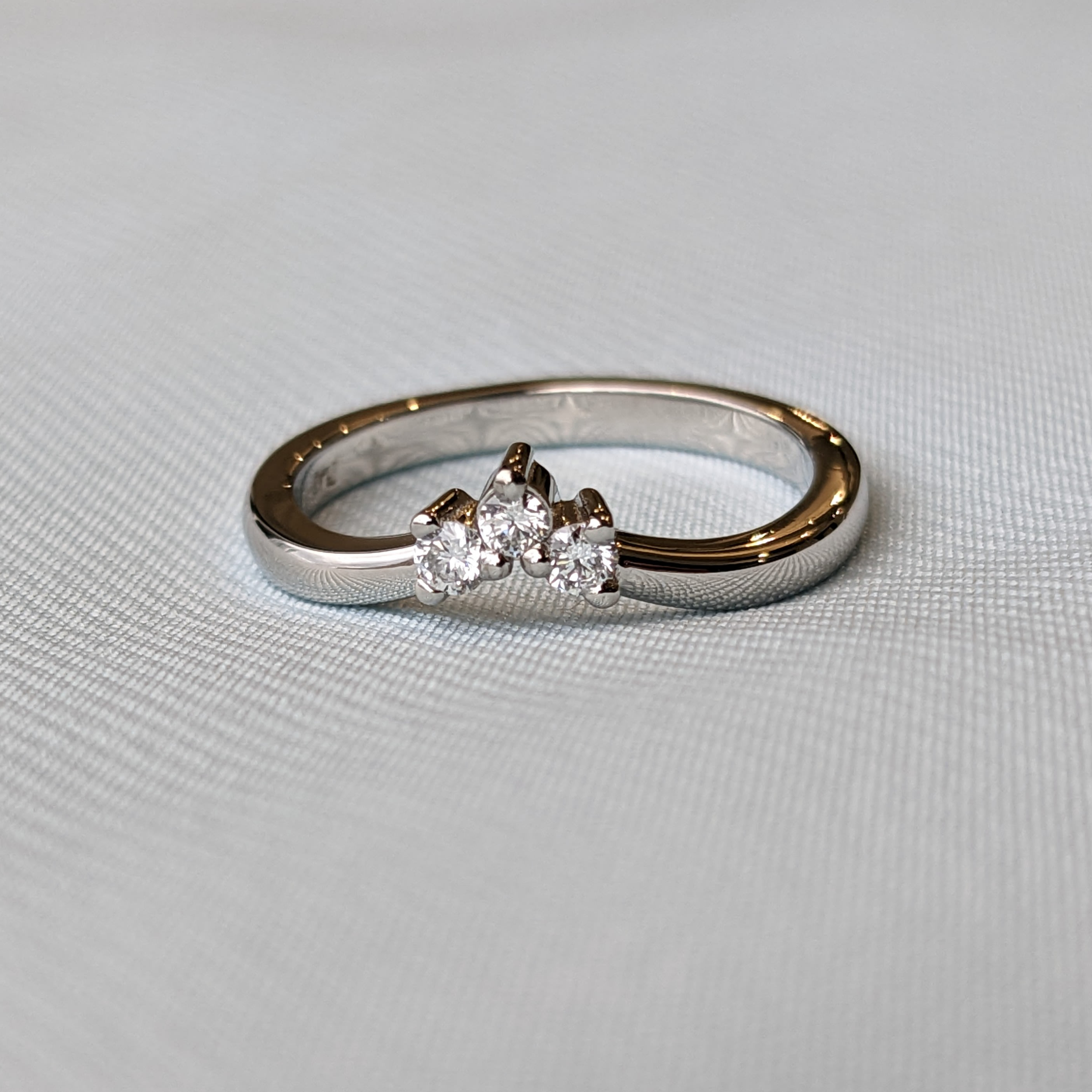 Dainty 3-stone engagement ring with small diamonds on a platinum band.