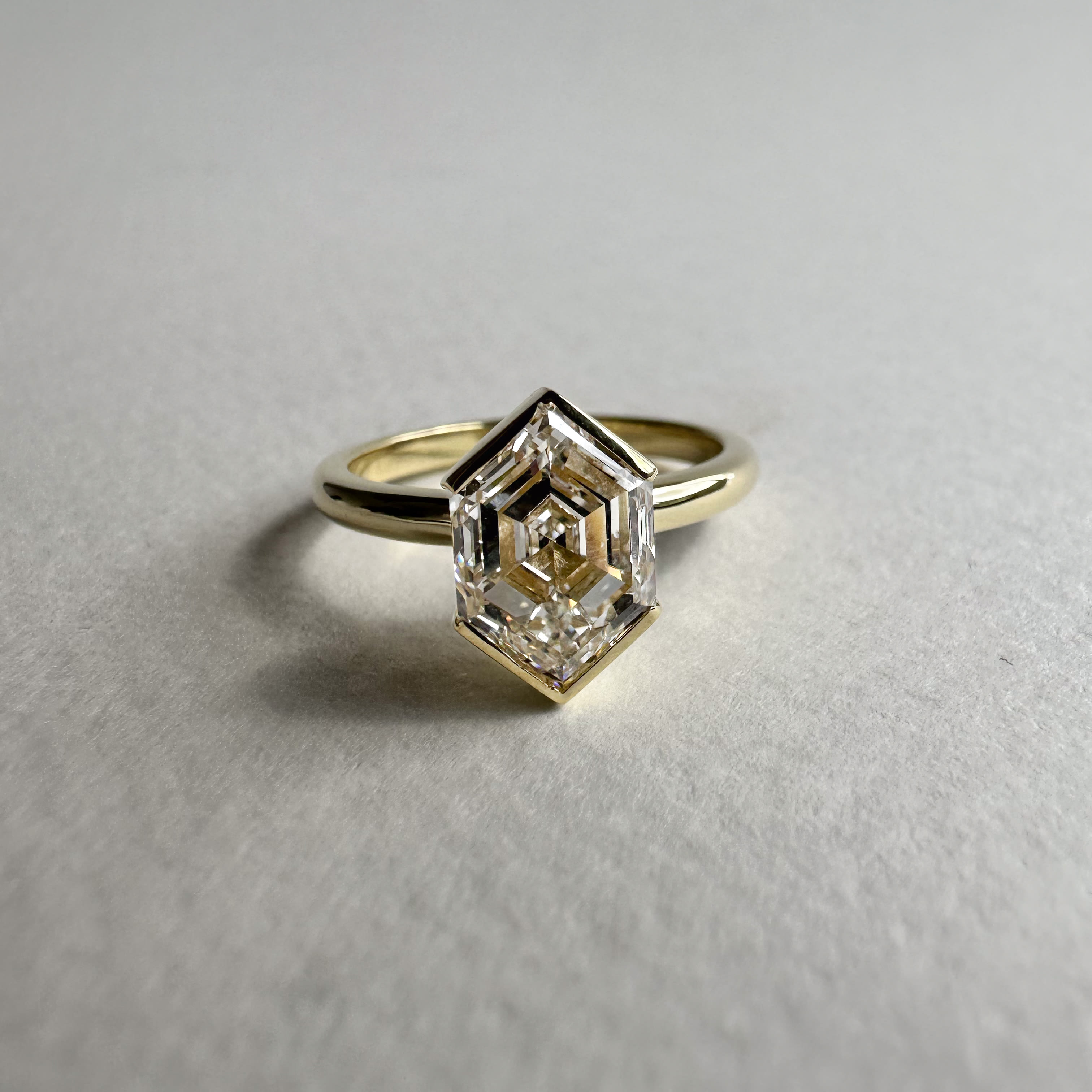 2 carat elongated hexagonal cut with half bezels in a yellow gold band