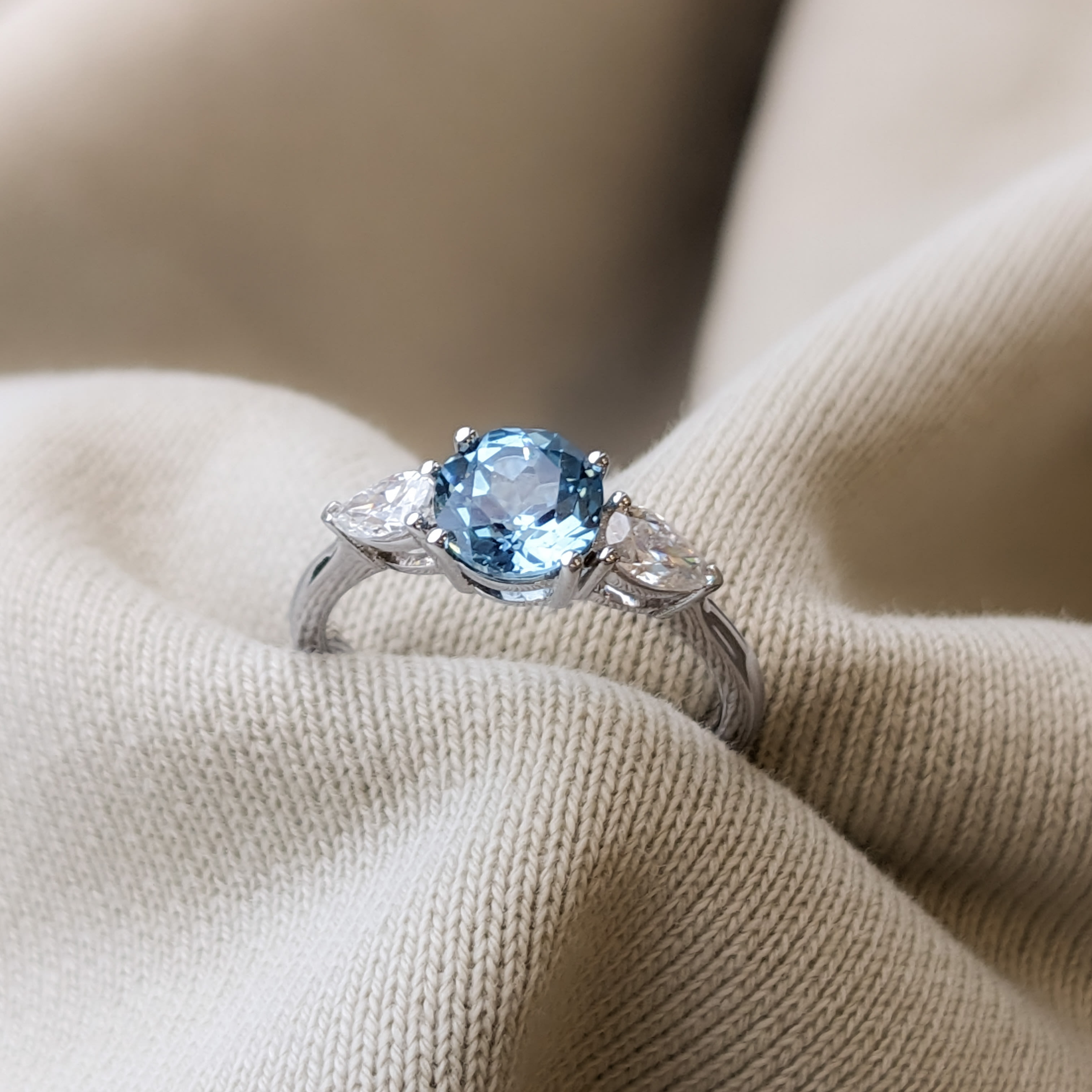 3 stone engagement ring featuring an aquamarine centre stone and two accenting pear diamonds in a white gold band