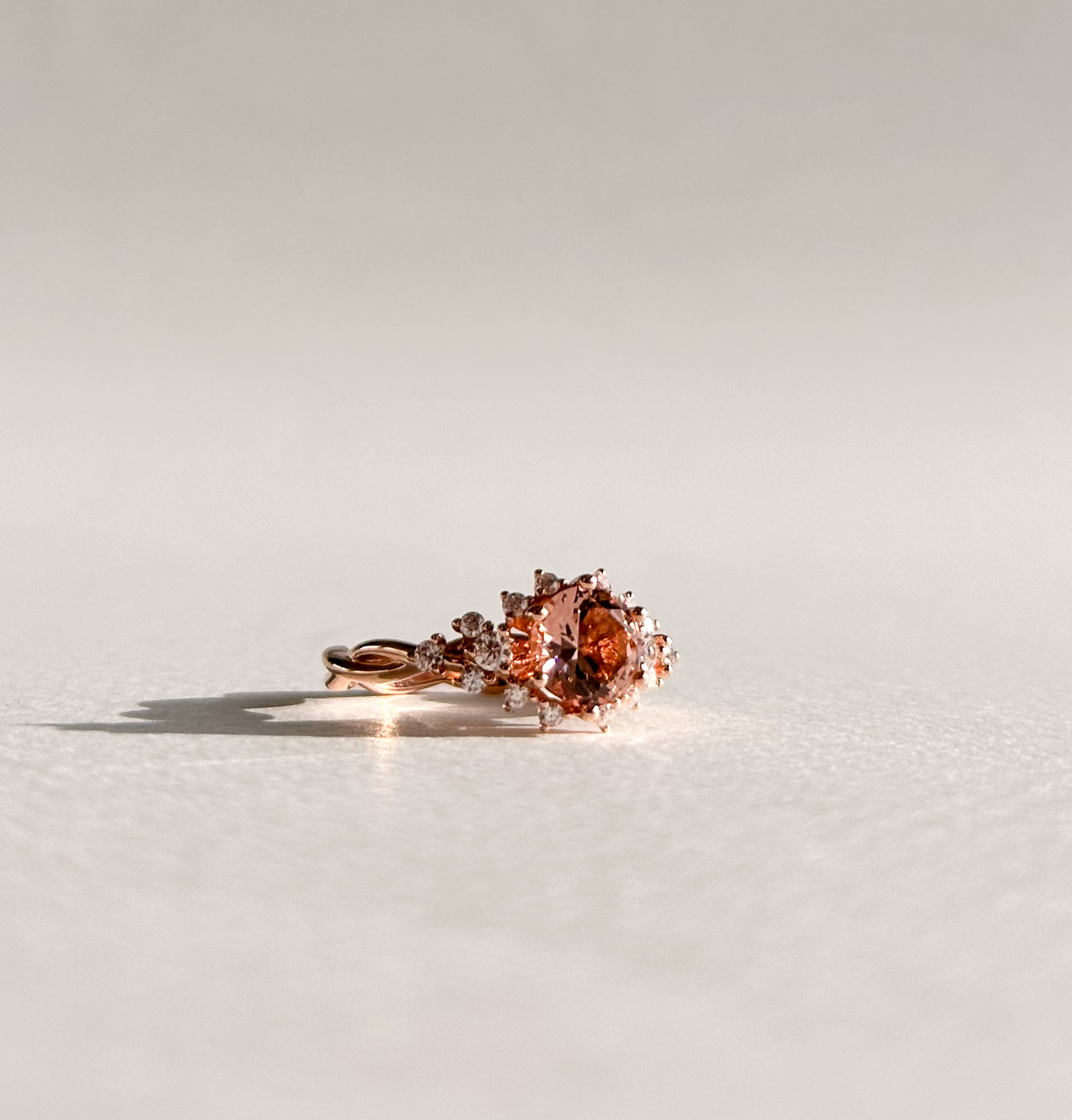 Round brilliant morganite featuring accenting diamonds on a twisted rose gold band