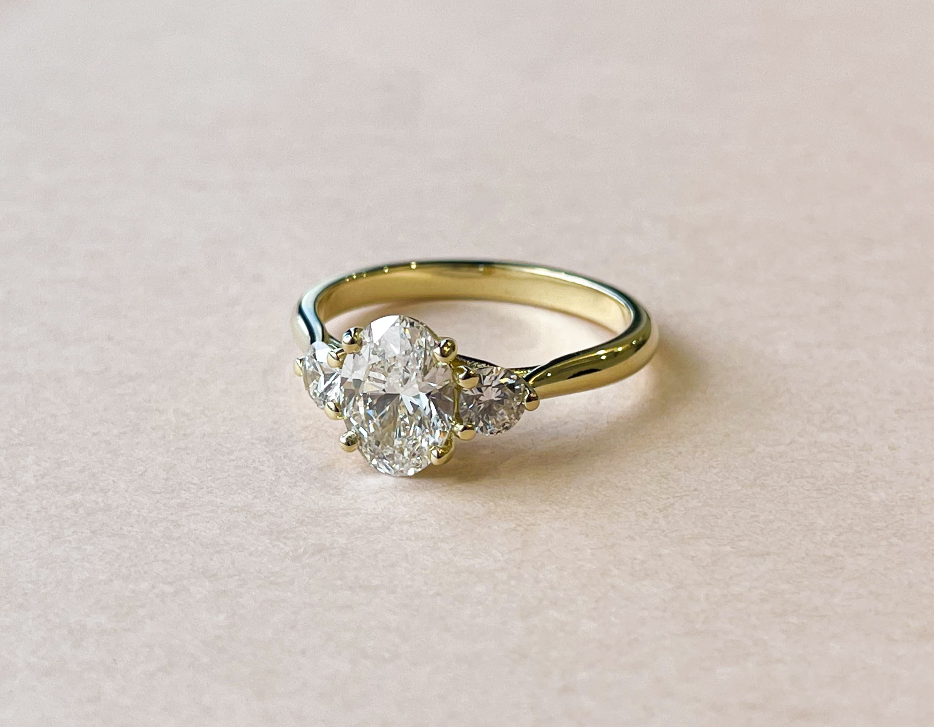 3 stone engagement ring featuring an oval centre stone and accenting round cut diamonds