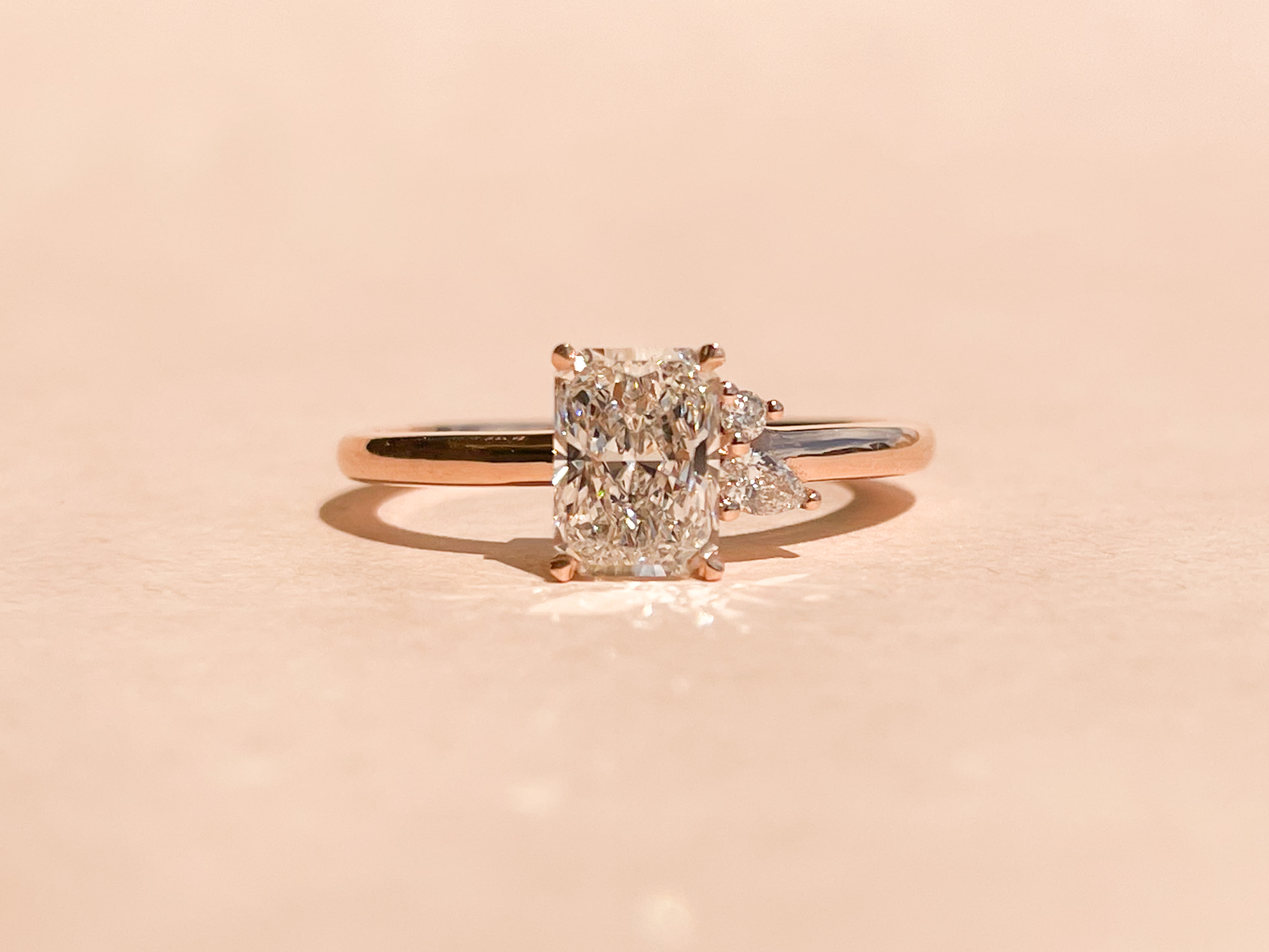 3 stone asymmetric designed engagement ring featuring an elongated radiant cut diamond with two smaller accenting pear cut diamonds 