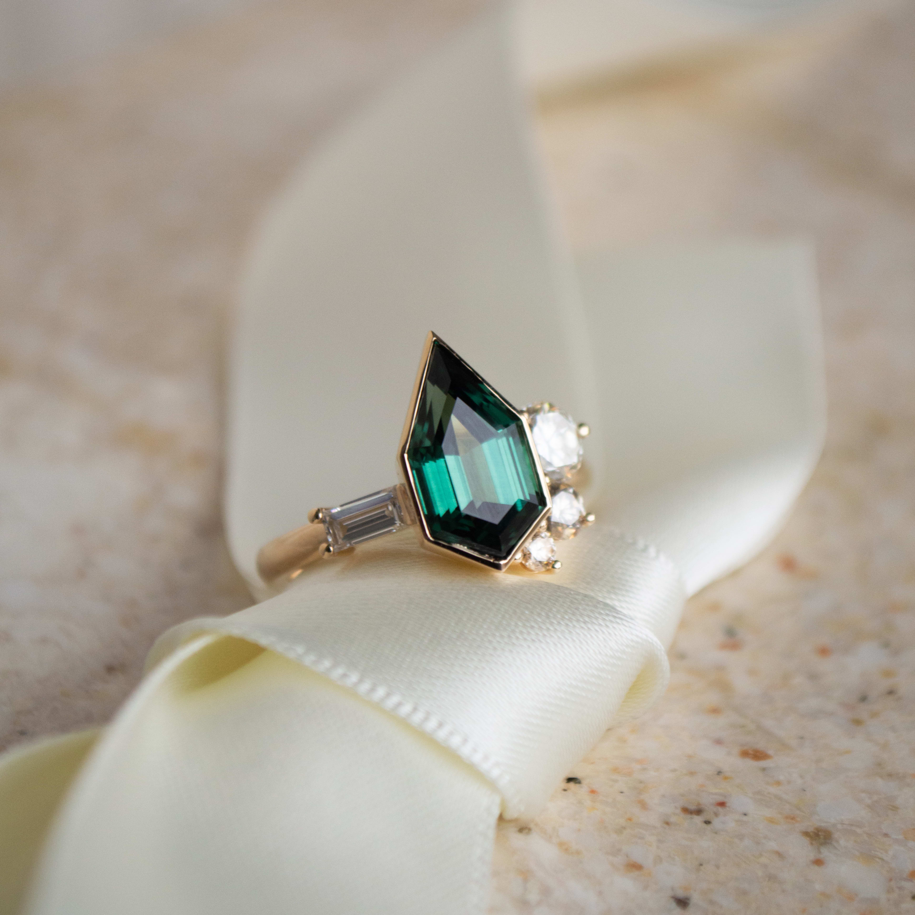 Custom hexagonal cut green sapphire in full bezel with asymmetrical accenting diamonds in yellow gold.