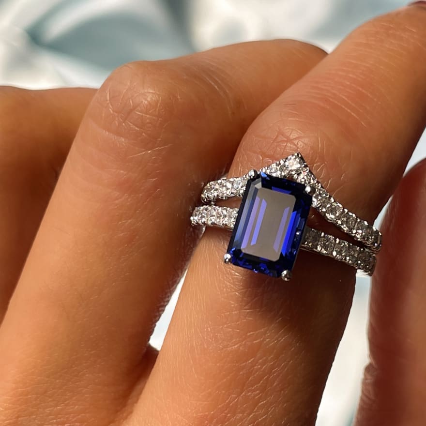Bridal set featuring a sapphire gemstone emerald cut engagement ring featuring pave diamonds with a matching tiara wedding ring in platinum