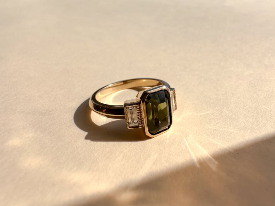 3 stone engagement ring featuring an emerald centre stone with two accenting diamonds in a 14k yellow gold band