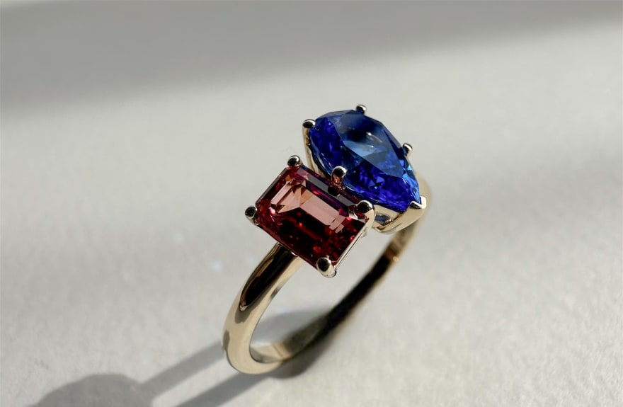 Toi et moi engagement ring featuring a 1 carat red moissanite and a 1.5 pear cut equivalent carat blue sapphire