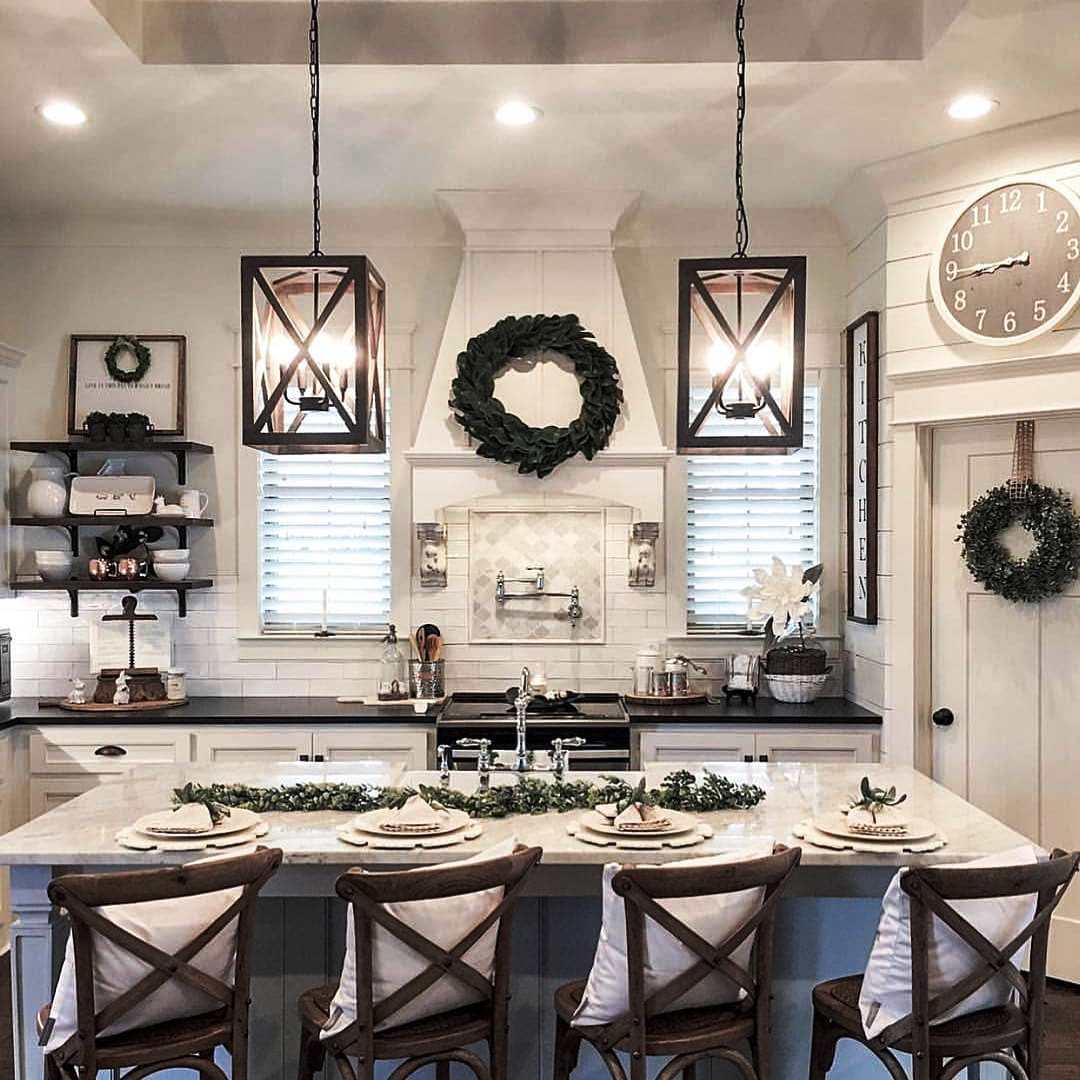 white cabinets and drawers, brown and gray marble countertop and backsplash, metal fridge, and metal light fixtures in a beige colored kitchen