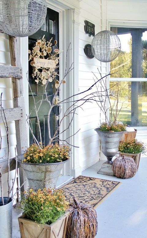 A crafty wreath made out of wood slices and twigs decorate a front door now add a couple of pumpkins and you get a great fall entrance.