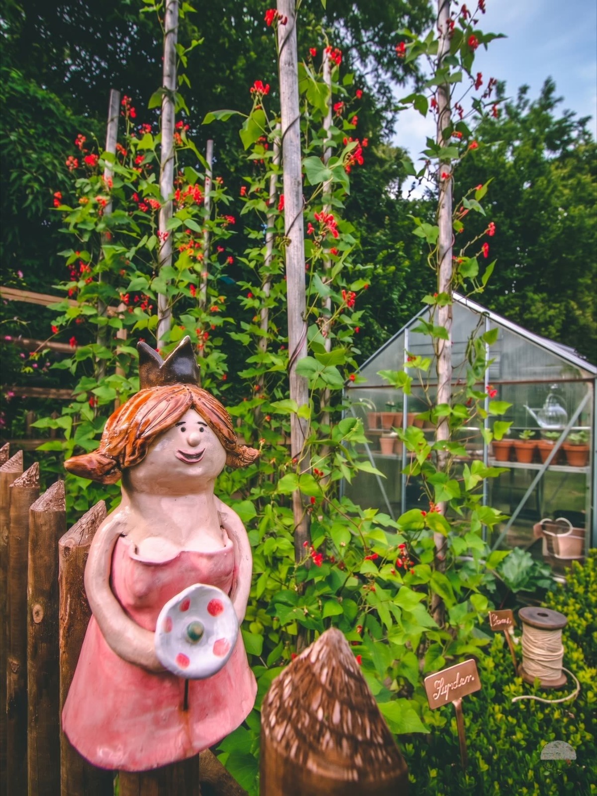 Gemüsegarten mit Stangenbohnen und Gewächshaus