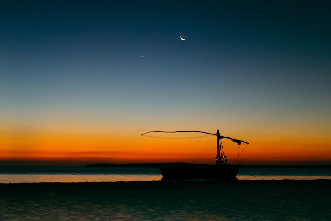silhouette of sail ship on sea during sunset