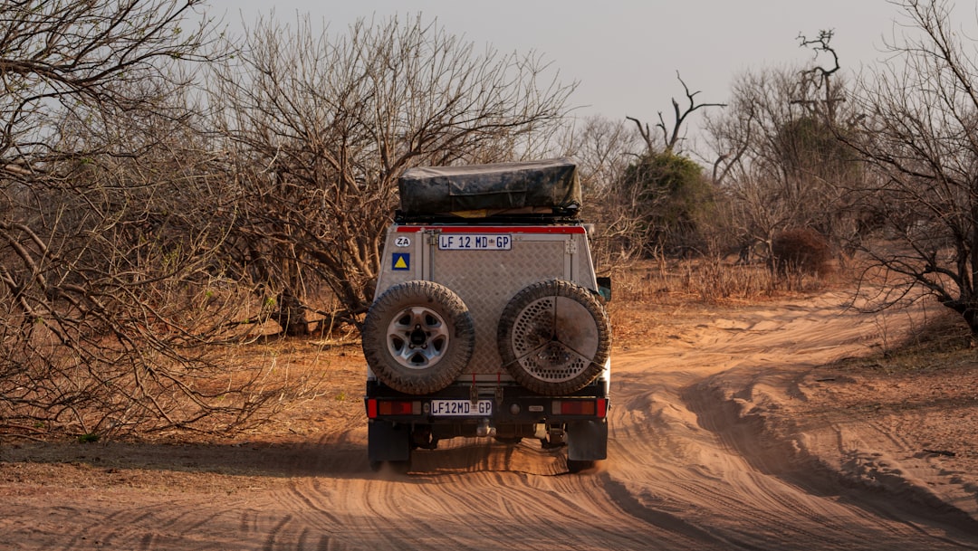 An off-road vehicle drives on a dusty track.
